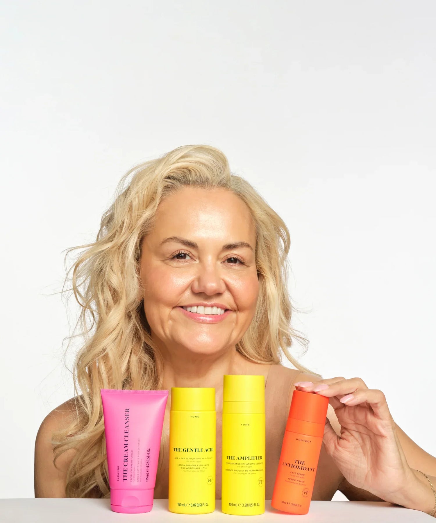 Skin Rocks by Caroline Hirons | Skincare products with smiling model showcasing cleanser, toner, essence, and serum