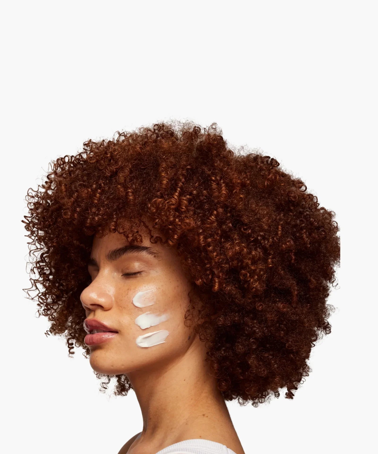 Skin Rocks by Caroline Hirons | Woman applying skincare cream on cheek with curly hair