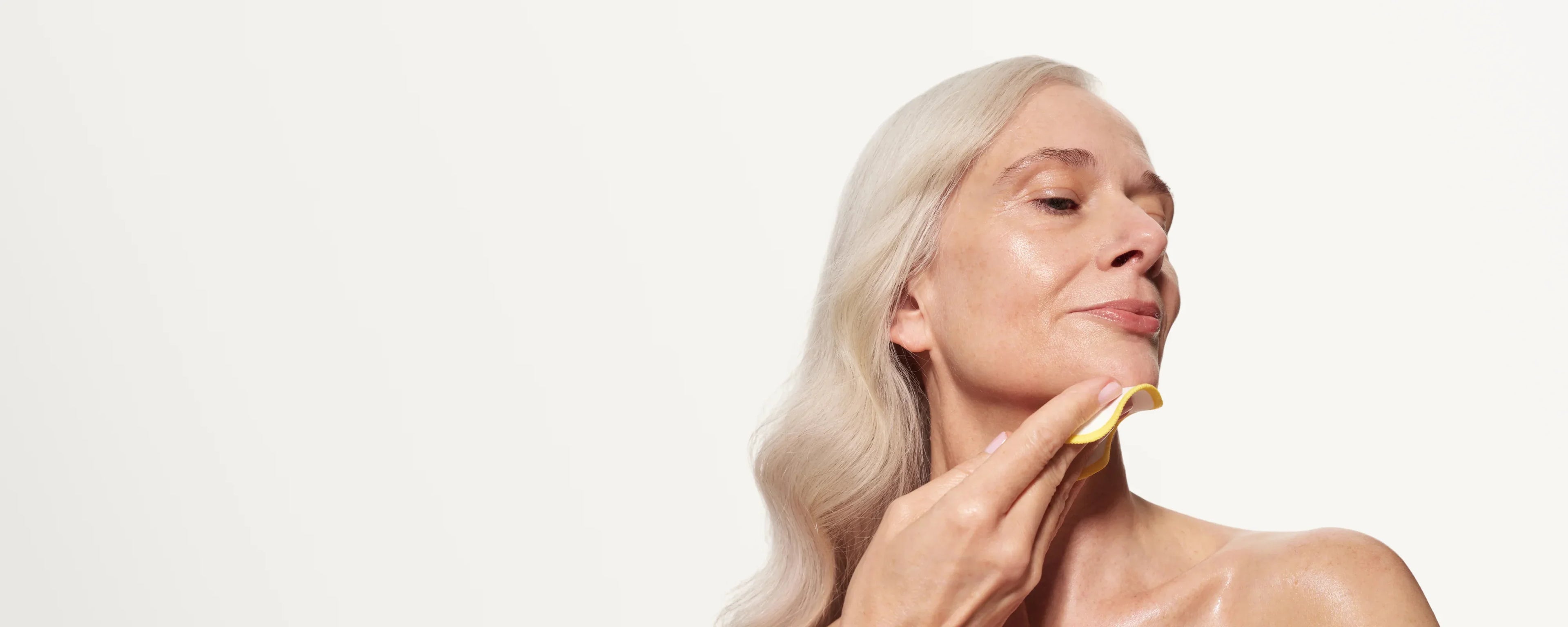 Skin Rocks by Caroline Hirons | Woman applying skincare with yellow cloth, glowing mature skin