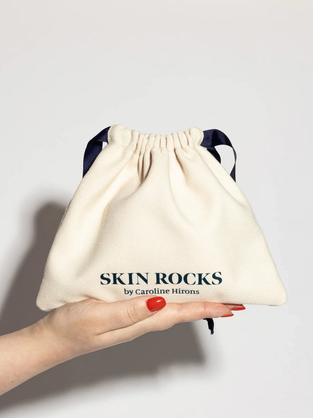 Skin Rocks by Caroline Hirons | cream drawstring bag with navy ribbon held by hand with red nails