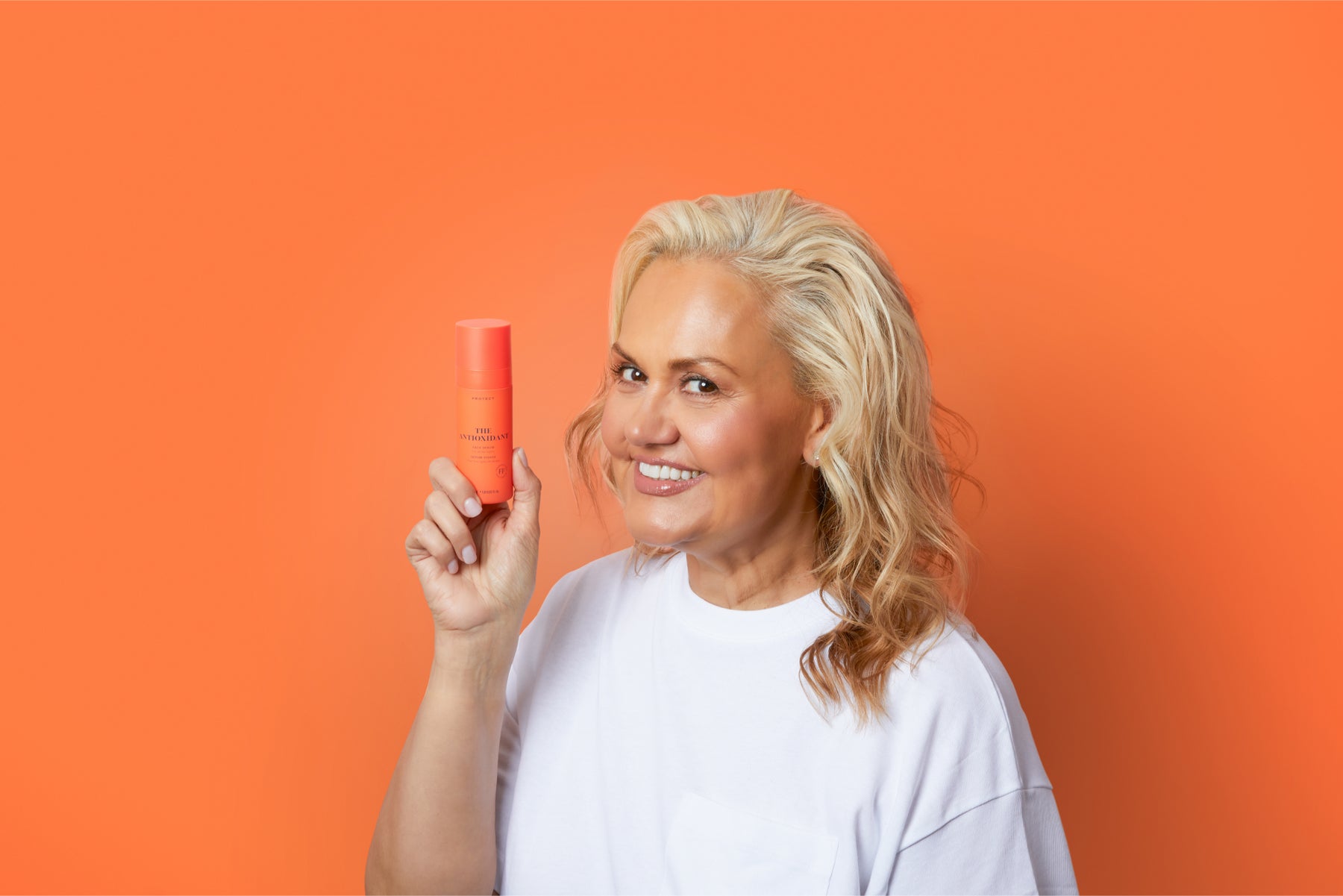 Skin Rocks' Founder, Caroline Hirons holding The Antioxidant against an orange background