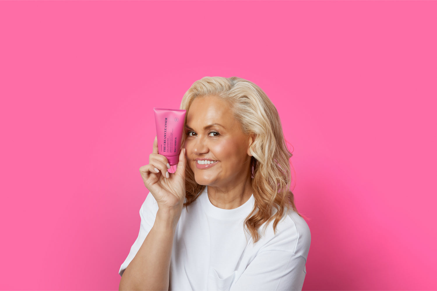 Skin Rocks' Founder, Caroline Hirons holding The Cream Cleanser against a rich pink background