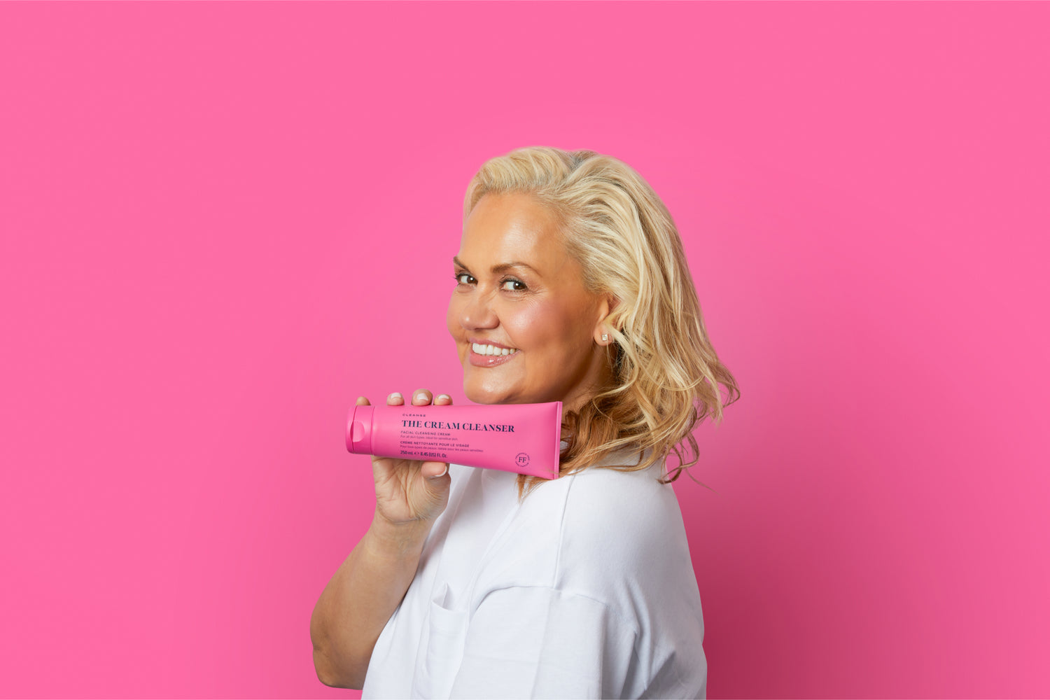 Skin Rocks' Founder, Caroline Hirons holding The Cream Cleanser Supersize against a rich pink background